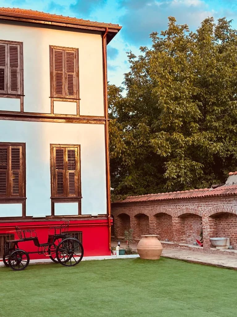 Bahçede siyah fayton ve tuğla kemerli duvar
